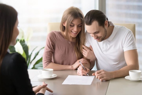 An excited couple signing a prenuptial agreement in front of a family law attorney.