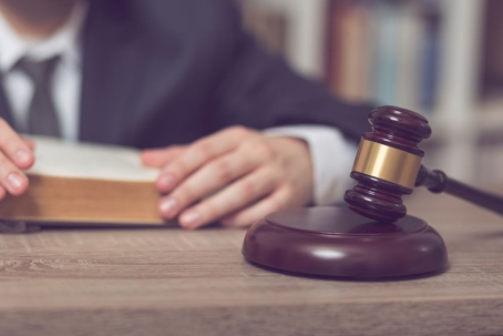 Man reading book on a table that has a gavel.